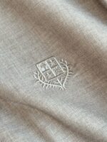 Tessuto elegante con ricamo di stemma heralico, dettagli raffinati e texture di alta qualità.