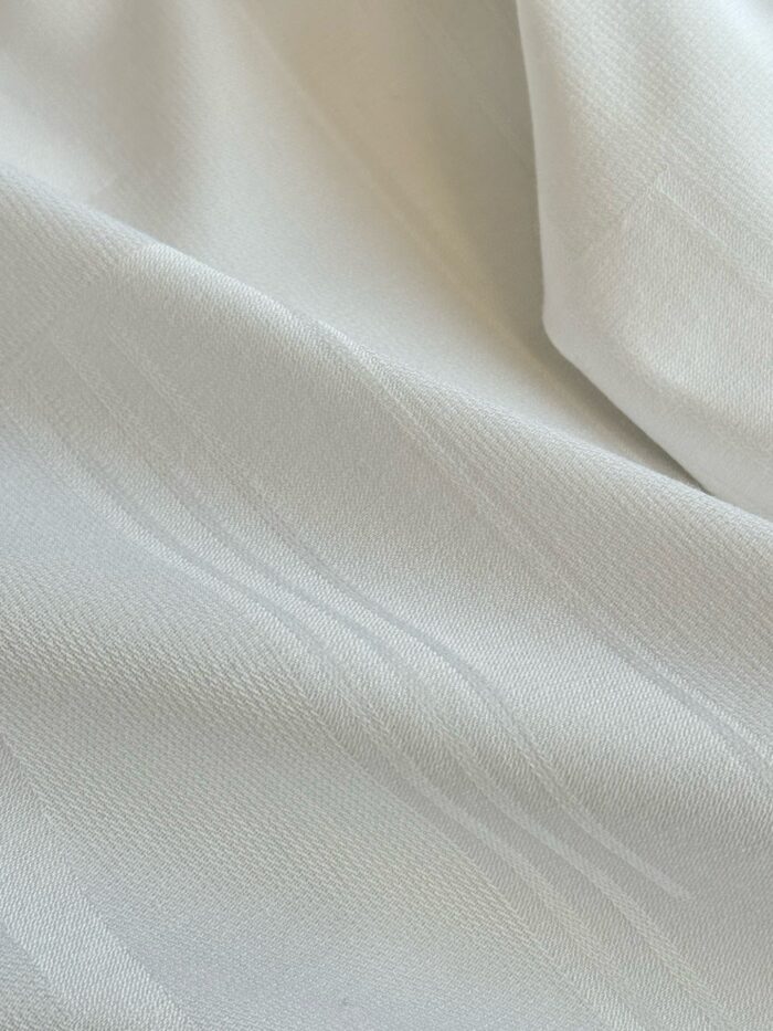 Tessuto leggero e raffinato con sottili righe dorate, ideale per abbigliamento e decorazioni eleganti.