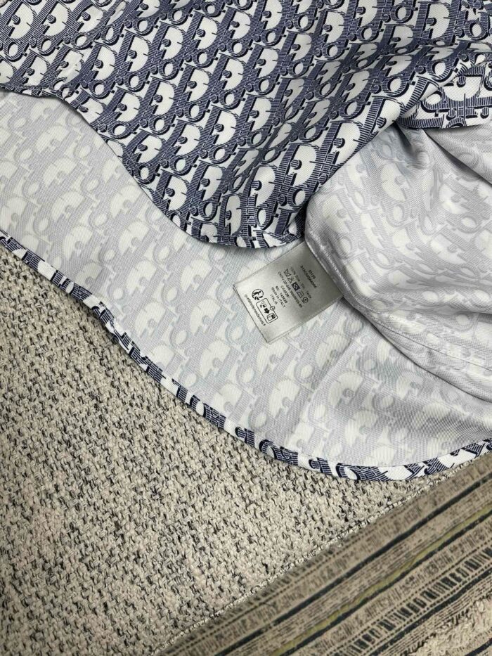 Tessuto con elefanti blu e grigi, interno con motivo delicato, perfetto per camicie eleganti e casual.