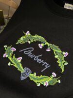 Maglia nera con ricamo Burberry, foglie verdi e fiori lilla.