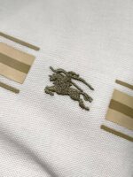 Tessuto di lusso con ricamo cavallo elegante e sottili strisce beige su sfondo bianco.