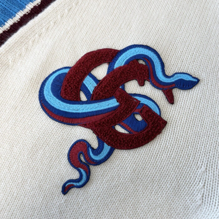 Ricamo di serpenti colorati su tessuto di alta qualità, dettaglio elegante e simbolico.