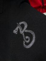 Logo ricamato in filo argentato su tessuto nero, elegante e di alta qualità.