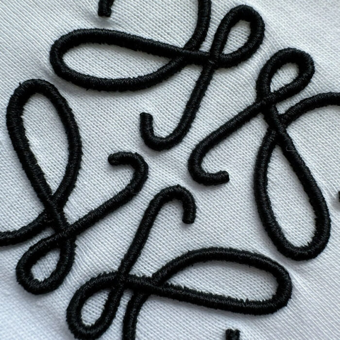 Patch ricamati neri su tessuto bianco, decorativi, artigianali e dal design elegante.