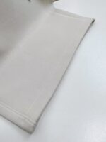 Tessuto beige liscio con orli rifiniti, elegante e versatile per arredamento e abbigliamento.