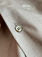 Dettaglio di tessuto elegante con bottone e ricamo discreto, stile raffinato e qualità superiore.