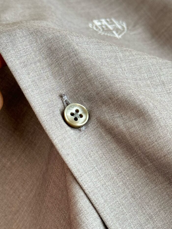 Dettaglio di tessuto elegante con bottone e ricamo discreto, stile raffinato e qualità superiore.