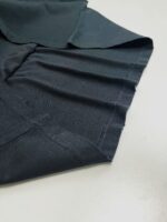 Dettagli di una camicia in tessuto scuro, con cuciture e texture raffinata.