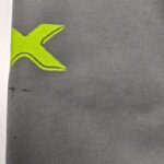 Tessuto grigio morbido con grafico a grande X giallo sportivo e dinamico.