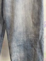 Dettaglio di jeans in denim chiaro e usurato, texture morbida, stile casual e vintage.