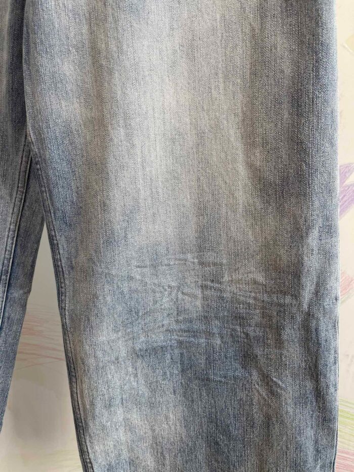 Dettaglio di jeans in denim chiaro e usurato, texture morbida, stile casual e vintage.