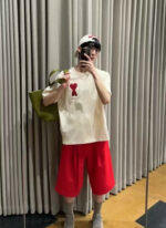 Giovane con outfit colorato, cappello, tote bag verde, selfie in ambiente moderno e luminoso.