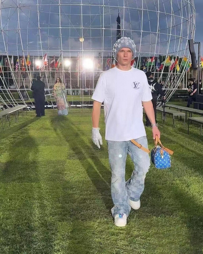 Jeune homme stylé en passerelle futuriste avec sneakers, sac luxury, ambiance vibrante et internationale.