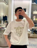 Selfie in negozio chic con T-shirt elegante con emblema dorato.