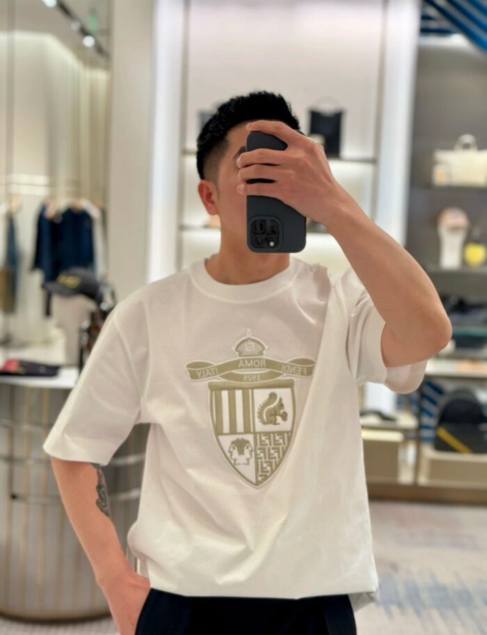 Selfie in negozio chic con T-shirt elegante con emblema dorato.