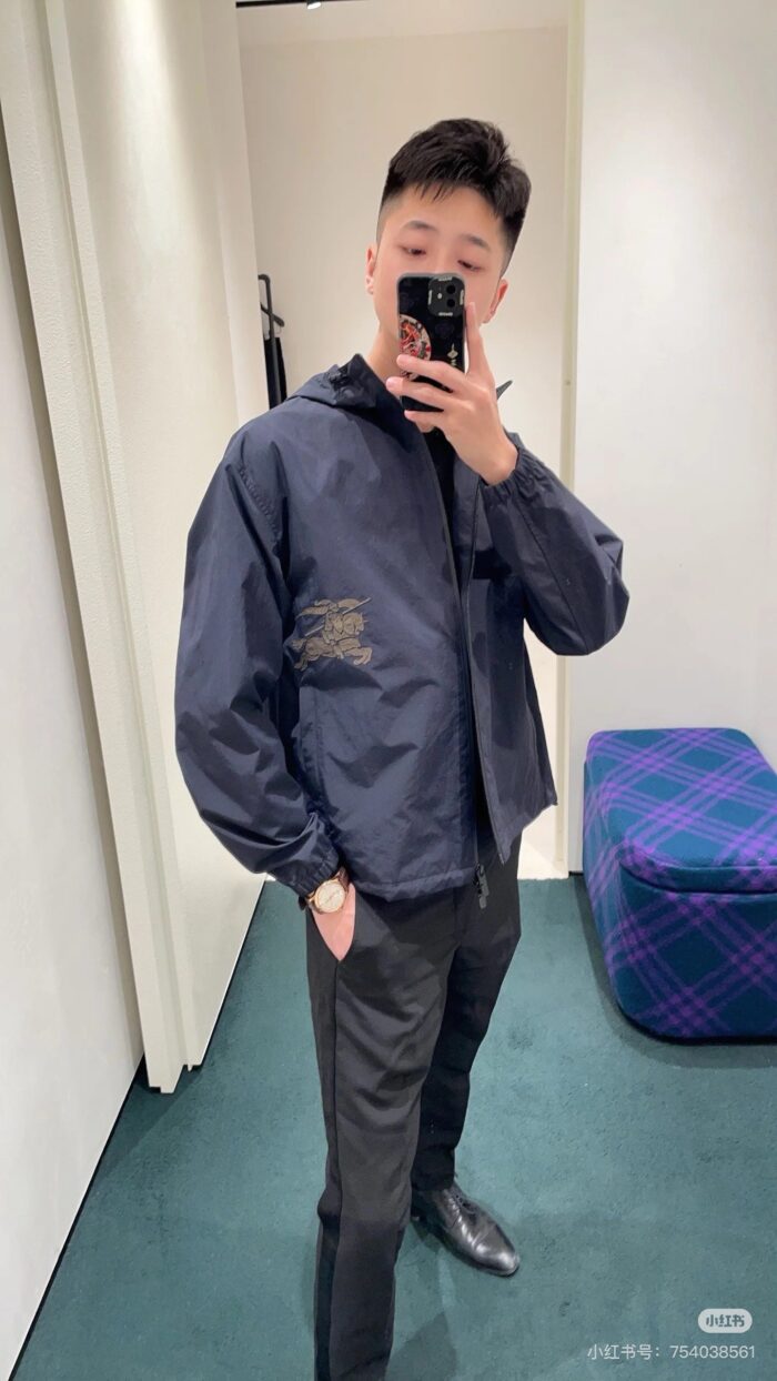 Selfie di uomo con giacca navy e pantaloni eleganti in spogliatoio moderno.