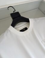 Maglietta bianca Fendi con logo elegante e design minimalista, esposta su appendino nero di alta qualità.