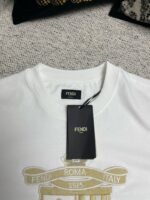 Maglietta bianca Fendi con logo dorato, dettagli eleganti e tag di autenticità.