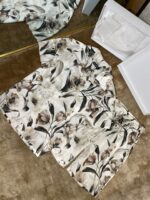 Elegant floral beige shirt unboxing on cozy carpet with packaging and soft lighting.
