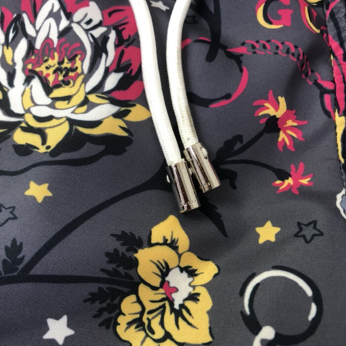 Felpa grigia con fiori colorati, nastrini e dettagli decorativi moderni e vivaci.