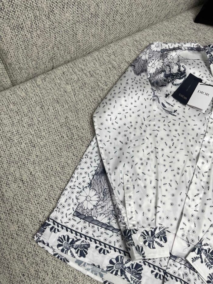 Camicia bianca con motivi floreali delicati su divano chiaro, elegante e casual.
