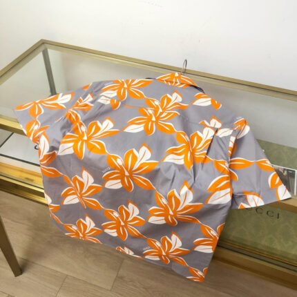 Camicia estiva a fiori arancioni e tropicali, in tessuto leggero e moderno.