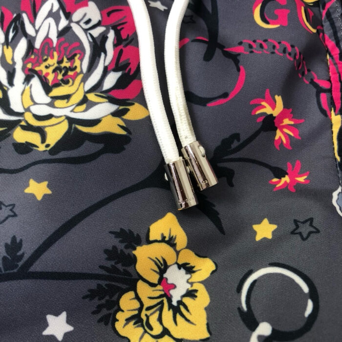 Tessuto floreale con stelle, nastri bianchi e dettagli metallici, ideale per moda e decorazione.