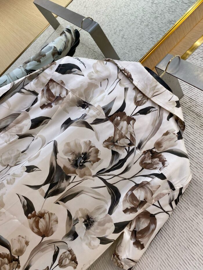 Elegant white floral blouse with beige taupe flowers, modern decor, and natural light backdrop.