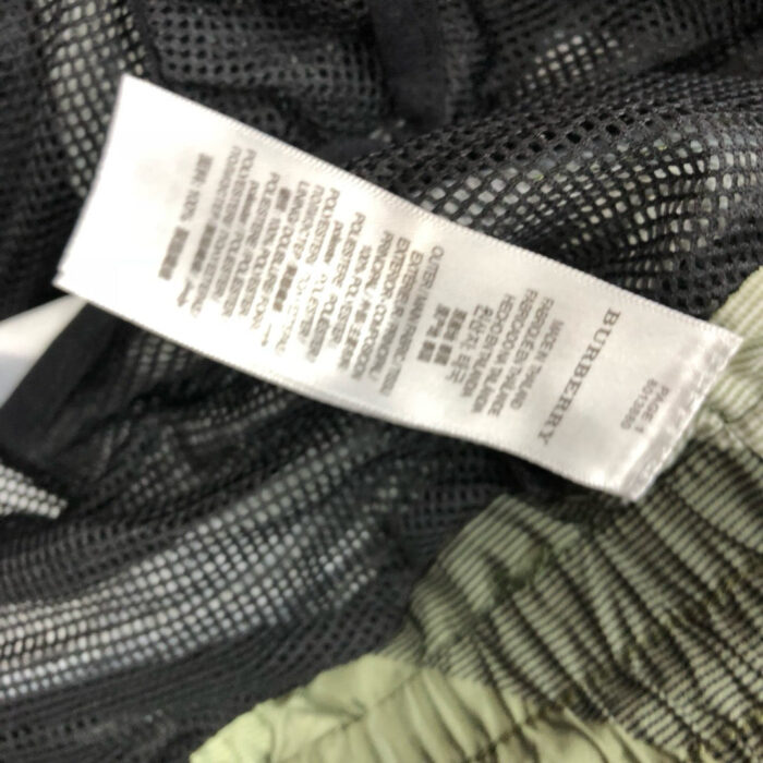 Etichetta di abbigliamento sportivo con istruzioni di cura e materiali, dettaglio vicino a tessuti tecnici.