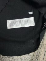Etichetta di cura interna su felpa nera, istruzioni e simboli di lavaggio.