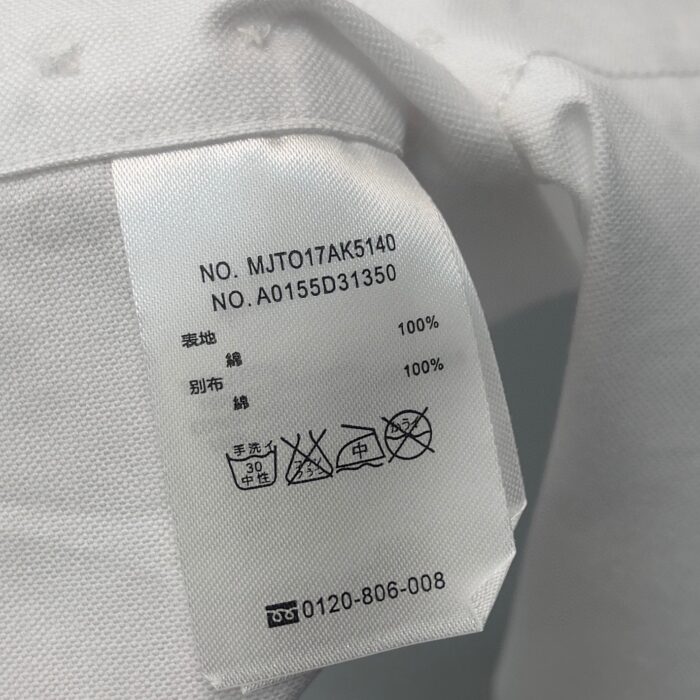 Etichetta di cura in cotone con simboli, codici e numero di contatto clienti.