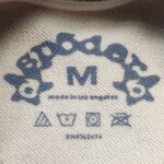 Etichetta abbigliamento Made in Los Angeles con simboli cura e design blu suggestivo.