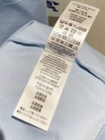 Etichetta di cura multilingue con simboli per lavaggio, asciugatura e stiratura.