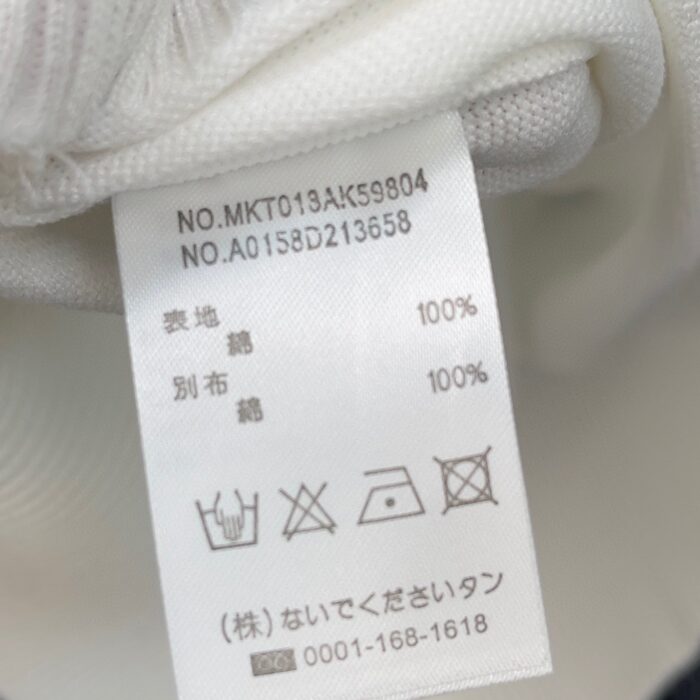 Etichetta di vestito in cotone con istruzioni di cura e codici identificativi.