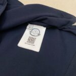 Etichetta interna in tessuto navy con logo, taglia M e QR code, dettaglio di qualità.