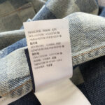 Etichetta di cura e composizione denim in cotone con istruzioni in italiano e inglese.