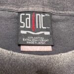 Etichetta Saint in cotone 100%, MADE IN JAPAN, con spada rossa e taglia XL.