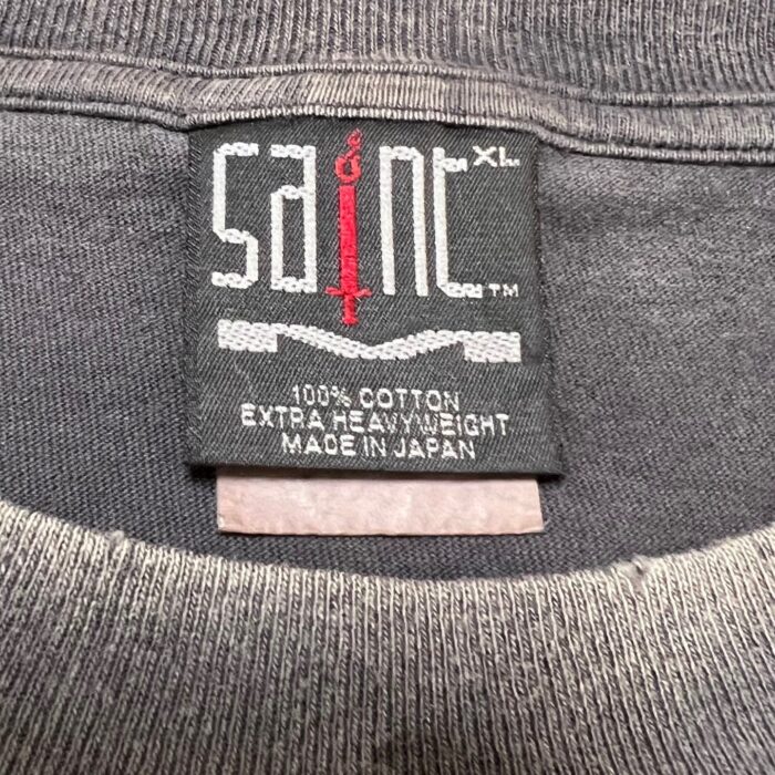 Etichetta Saint in cotone 100%, MADE IN JAPAN, con spada rossa e taglia XL.