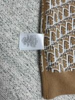 Tessuto con motivo geometrico, bordo marrone e etichetta di cura, ideale per abbigliamento.