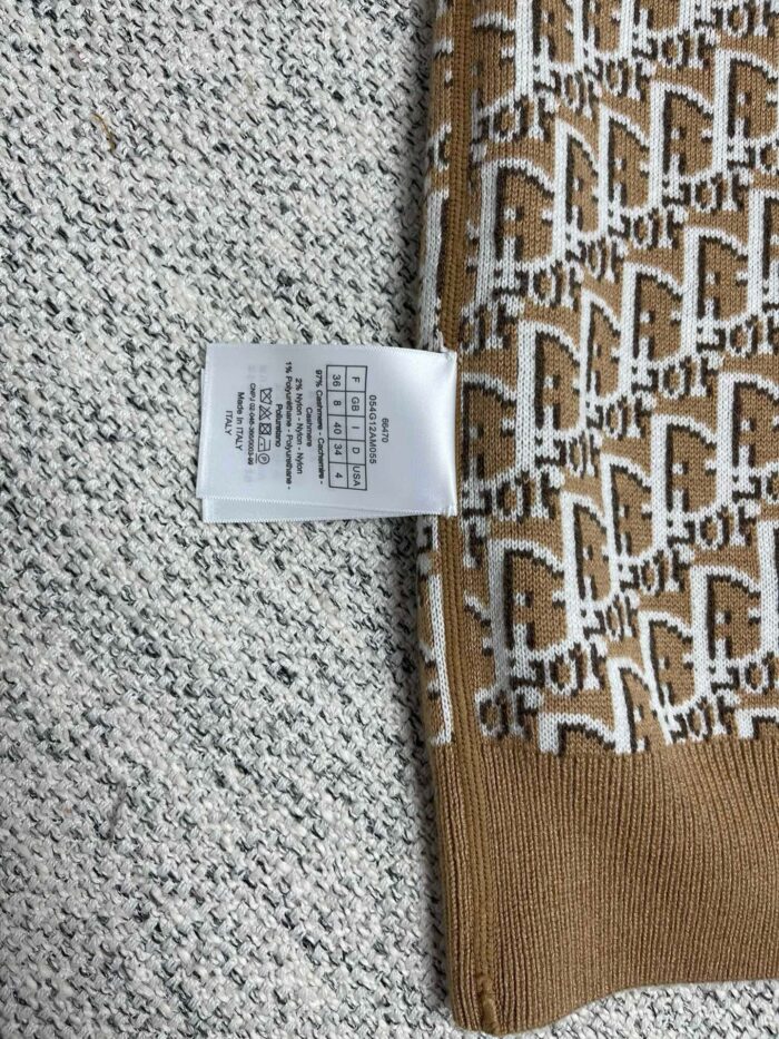 Tessuto con motivo geometrico, bordo marrone e etichetta di cura, ideale per abbigliamento.