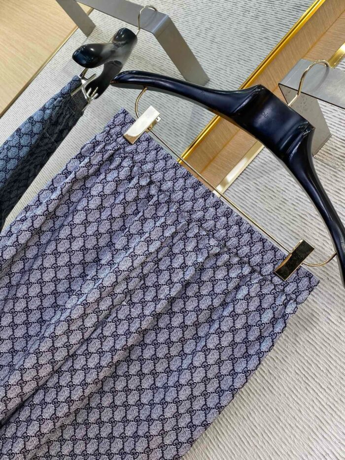 Pantaloni slim geometrici in blu e grigio su gancio nero elegante, stile moderno e raffinato.