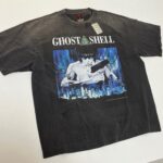 T-shirt nera vintage Ghost in the Shell, design cyberpunk e lettering audace, perfetta per fan anime.