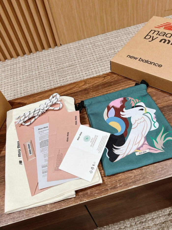 Set regalo con borsa teal, dettagli informativi e scatola New Balance su superficie in legno.