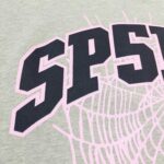Maglietta verde con logo SPSP e dettagli in ragnatela rosa, stile sportivo e giovanile.