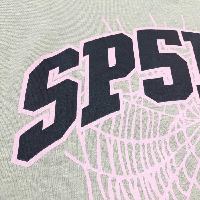 Maglietta verde con logo SPSP e dettagli in ragnatela rosa, stile sportivo e giovanile.
