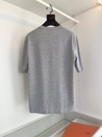 Maglietta grigia semplice con girocollo, vista da dietro, ideale per uno stile casual e versatile.