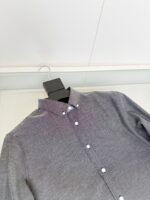 Camicia grigia moderna con logo discreto, bottoni bianchi e stile versatile per ogni occasione.
