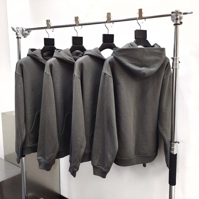 Lotta di 4 felpe grigie con cappuccio su esposizione minimalista in boutique elegante.