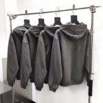 Banda di felpe grigie casual su scaffale metallico in negozio moderno.