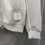 Felpa grigia minimalista con zip, etichetta davanti e dettagli comodi, stile urbano e casual.